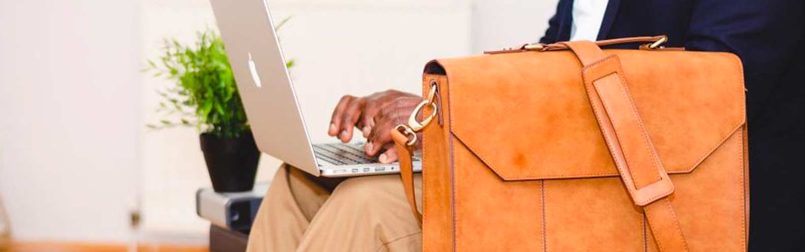 Man types on laptop while traveling.